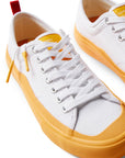 Pair of Dipped Kicks white shoes with yellow soles